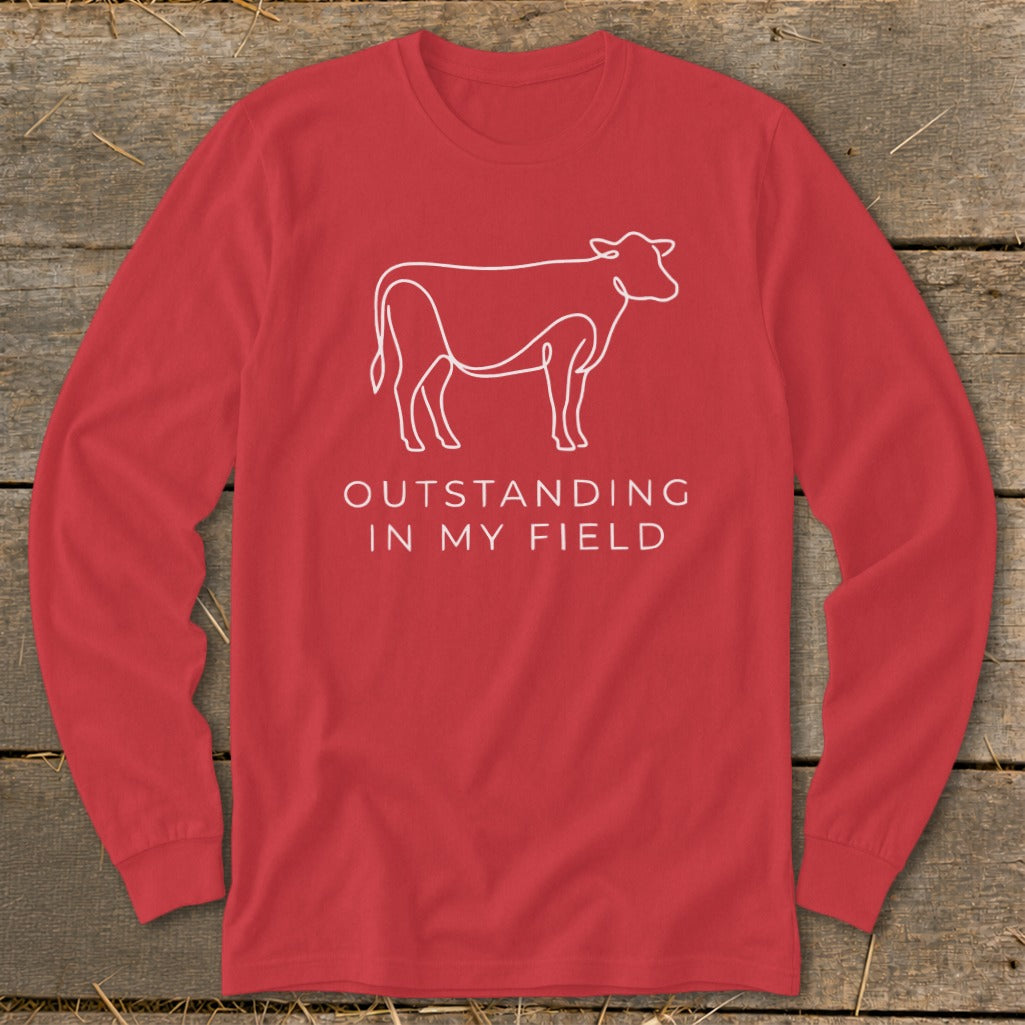 Red long-sleeve shirt with white cow outline and text "OUTSTANDING IN MY FIELD".