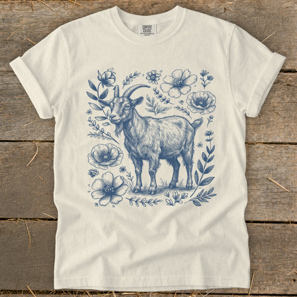 White t-shirt with a blue ink sketch of a goat surrounded by flowers and leaves.