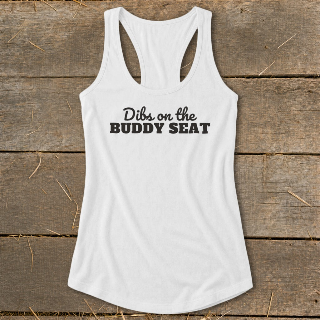 White tank top with black text "Dibs on the BUDDY SEAT" on rustic wood background.