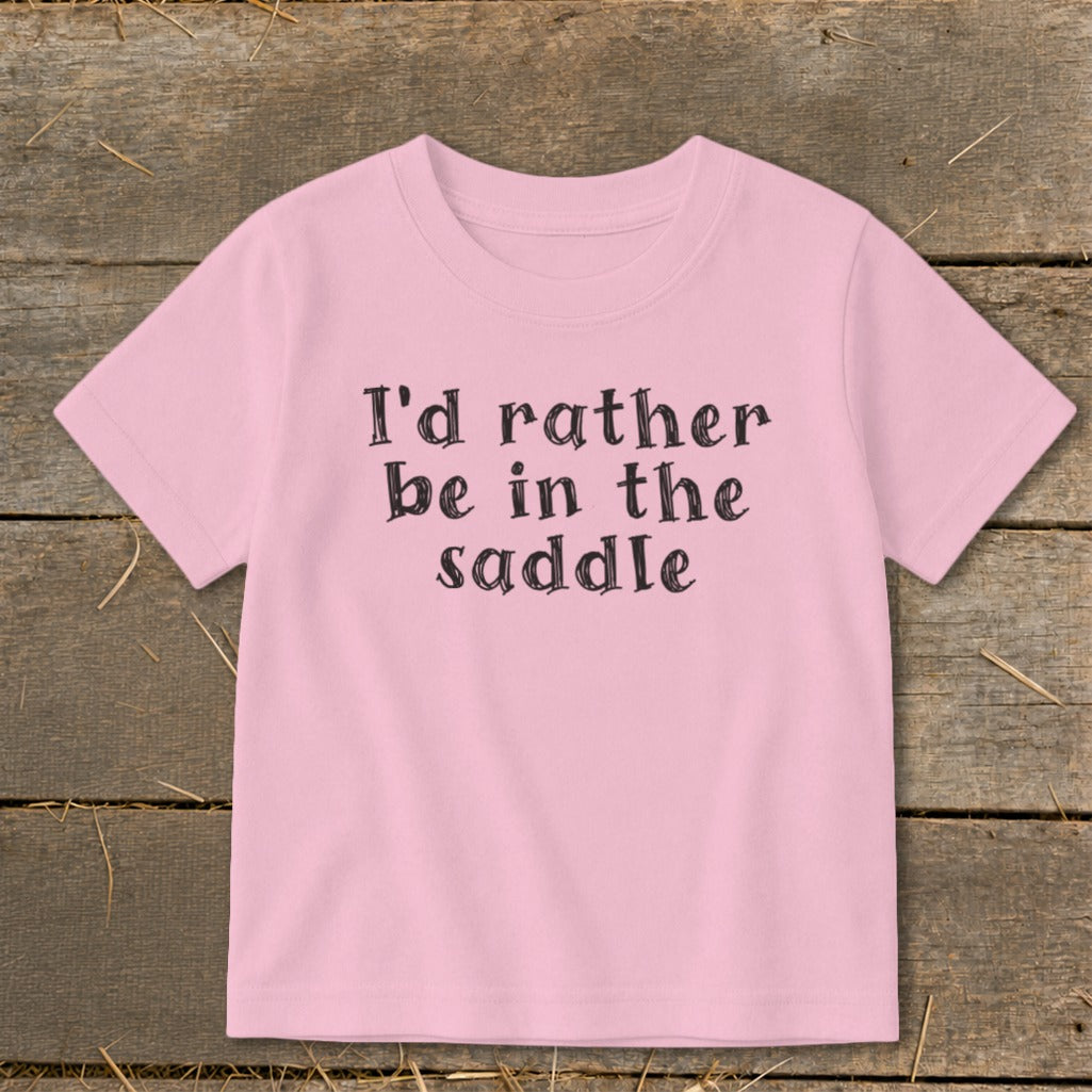Pink t-shirt with black text that says "I'd rather be in the saddle".