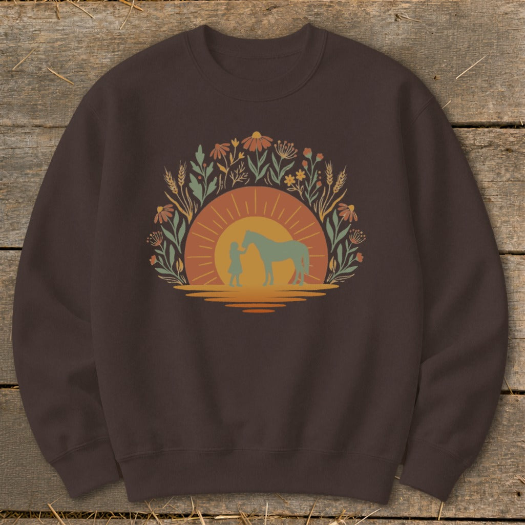 Brown sweatshirt with a sunset graphic of a person and horse surrounded by flowers.