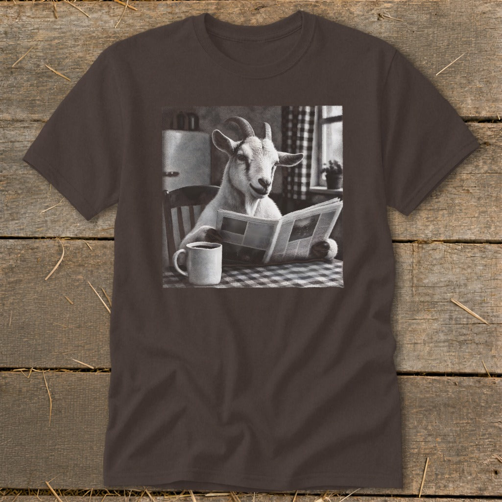 A dark brown t-shirt featuring a black and white graphic of a goat reading a newspaper at a table with a mug of coffee.