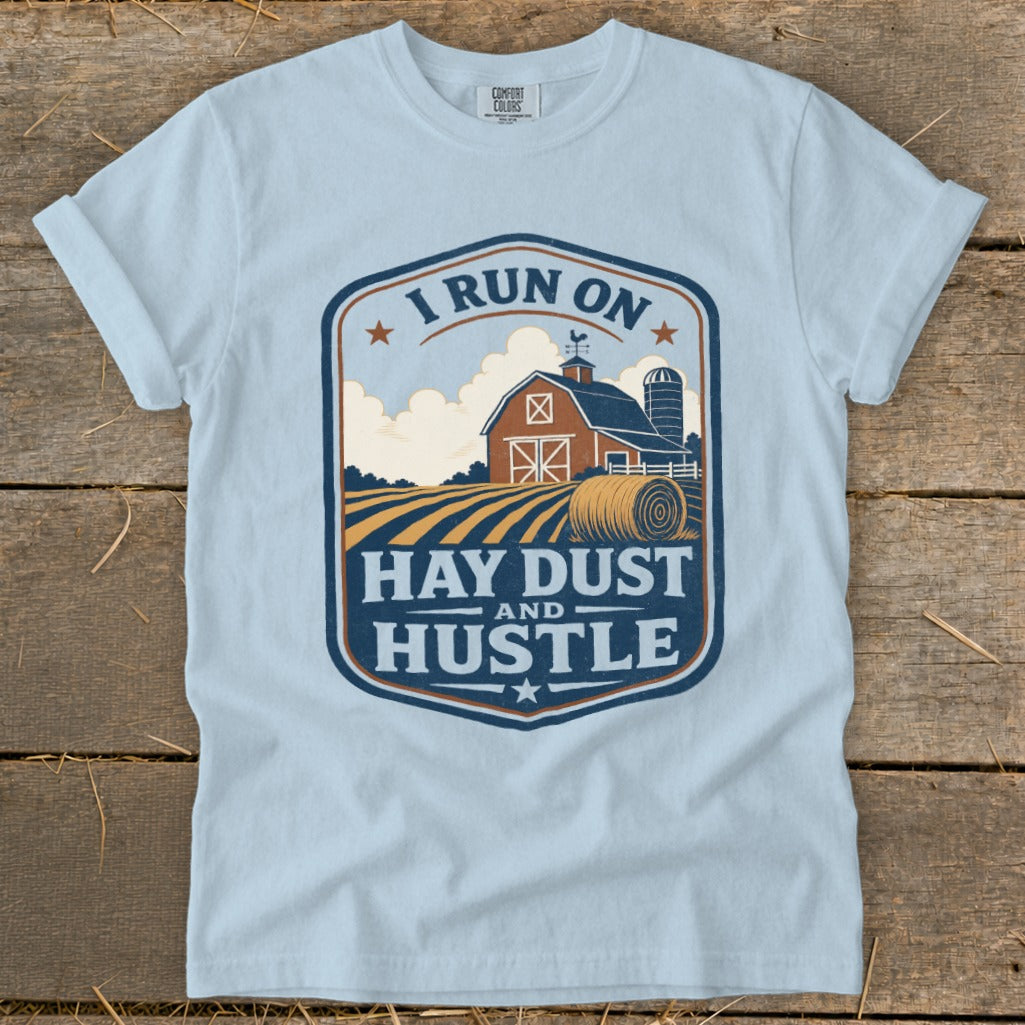 Light blue t-shirt with a farm scene and text "I RUN ON HAY DUST AND HUSTLE."