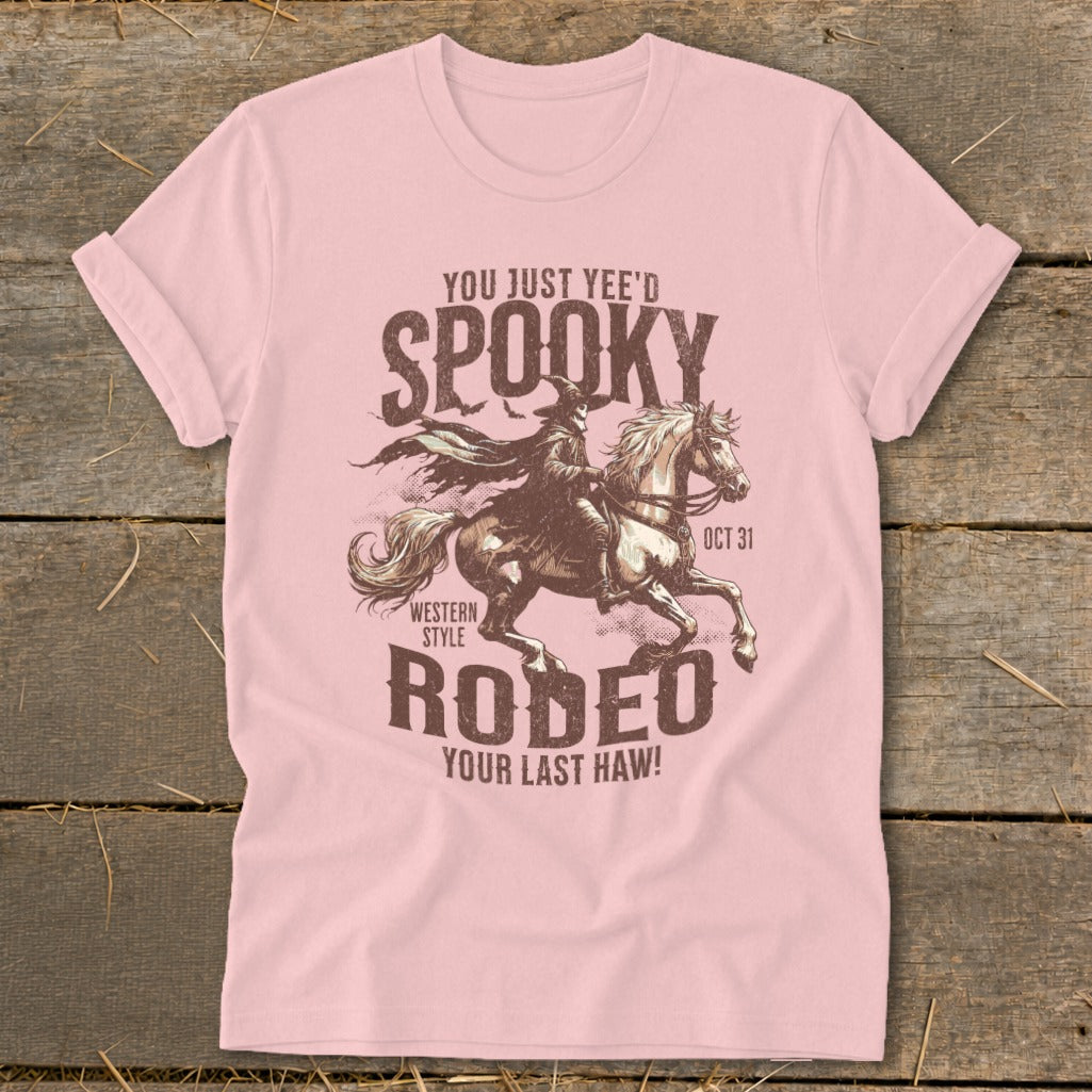 Pink t-shirt with "Spooky Rodeo" graphic of a robed figure on a horse, "Oct 31."