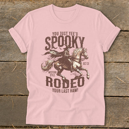 Pink t-shirt with "Spooky Rodeo" graphic of a robed figure on a horse, "Oct 31."