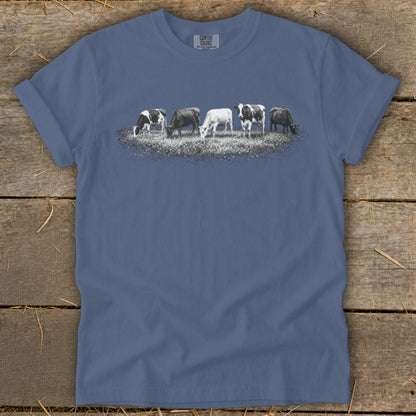 Herd of black and white cows grazing in a field graphic on a blue t-shirt.