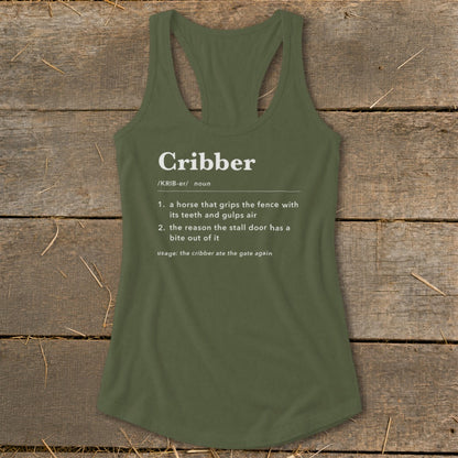 An olive green racerback tank top featuring white dictionary-style definition text about a cribber horse laid flat on a rustic wooden background.