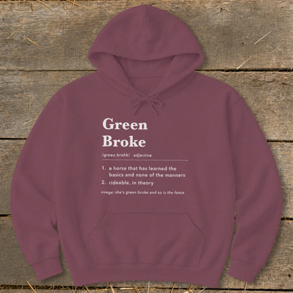Maroon hoodie with white text defining Green Broke laid flat on rustic wood.