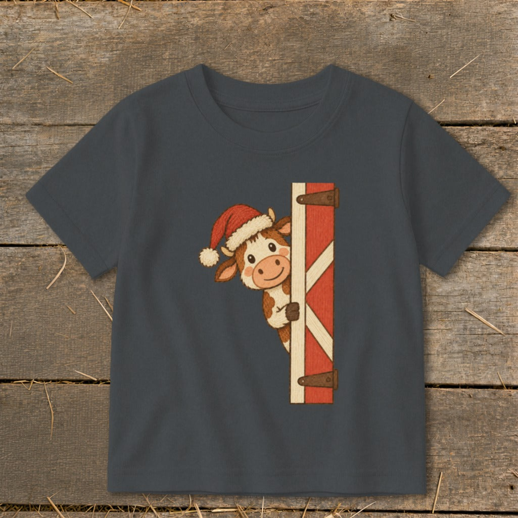Dark grey t-shirt with a cartoon cow wearing a Santa hat peeking from behind a barn door.