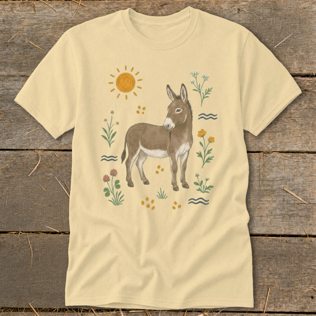 Light yellow t-shirt with a donkey surrounded by flowers, sun, and wavy lines.