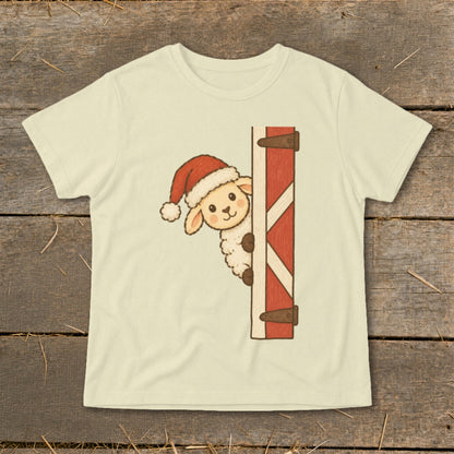 Cream t-shirt with a cartoon sheep wearing a Santa hat peeking from behind a red barn door.