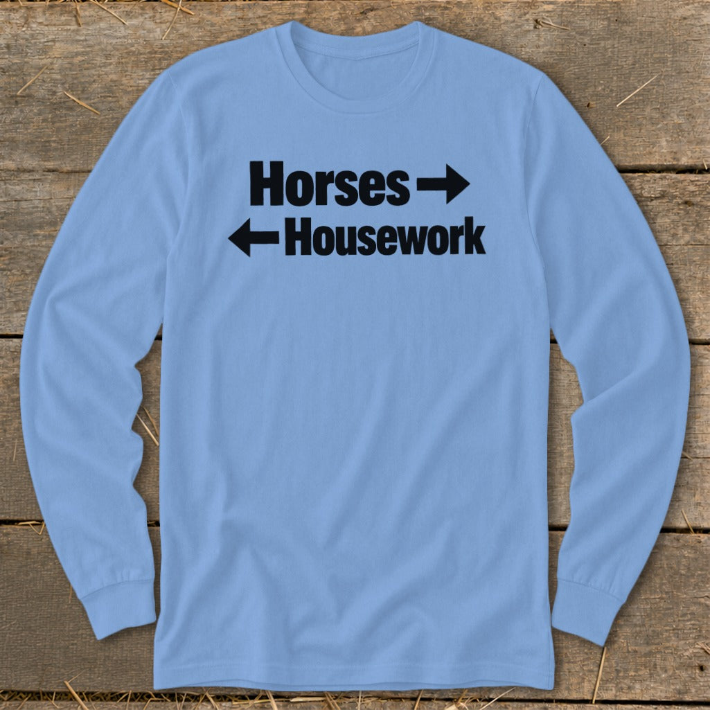 Light blue long-sleeve t-shirt with black text that reads "Horses" with a right arrow above "Housework" with a left arrow.