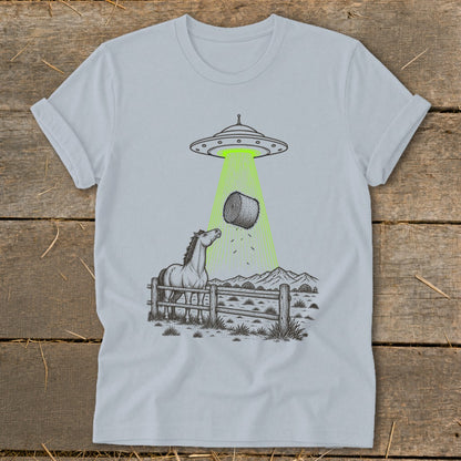 UFO abducts hay bale above a horse in a fenced field with mountains.