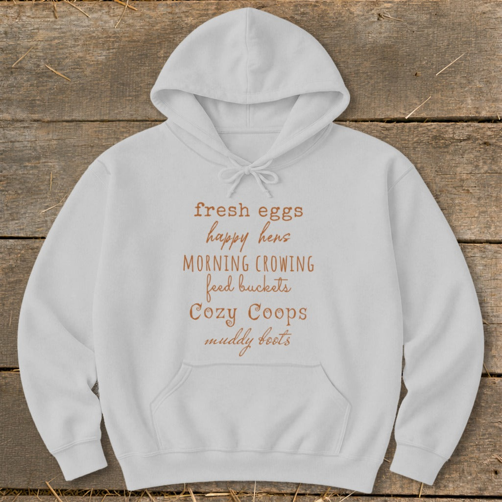 White hoodie with text "fresh eggs happy hens MORNING CROWING feed buckets Cozy Coops muddy boots".
