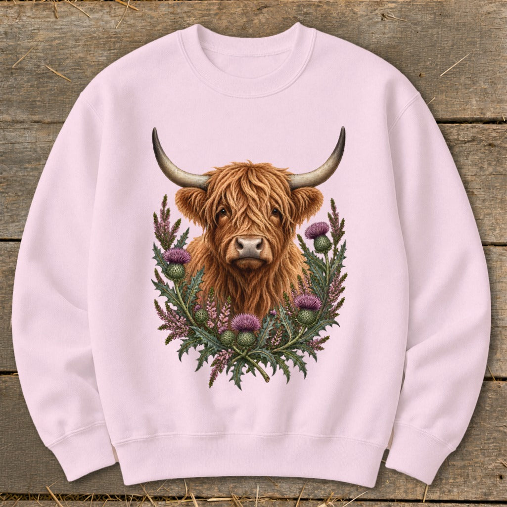 Pink sweatshirt with a fluffy highland cow and thistles graphic print.