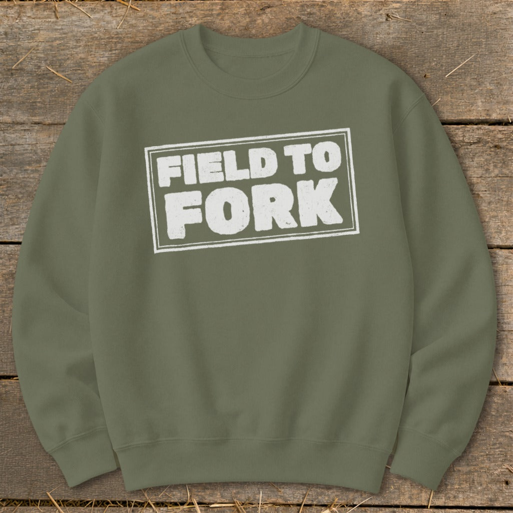 An olive green crewneck sweatshirt featuring a white distressed box graphic with the text FIELD TO FORK.