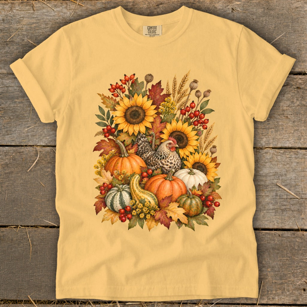 Yellow t-shirt with a watercolor fall harvest design featuring sunflowers, pumpkins, gourds, berries, and a hen.