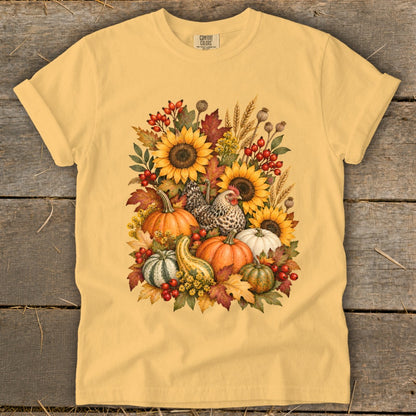 Yellow t-shirt with a watercolor fall harvest design featuring sunflowers, pumpkins, gourds, berries, and a hen.