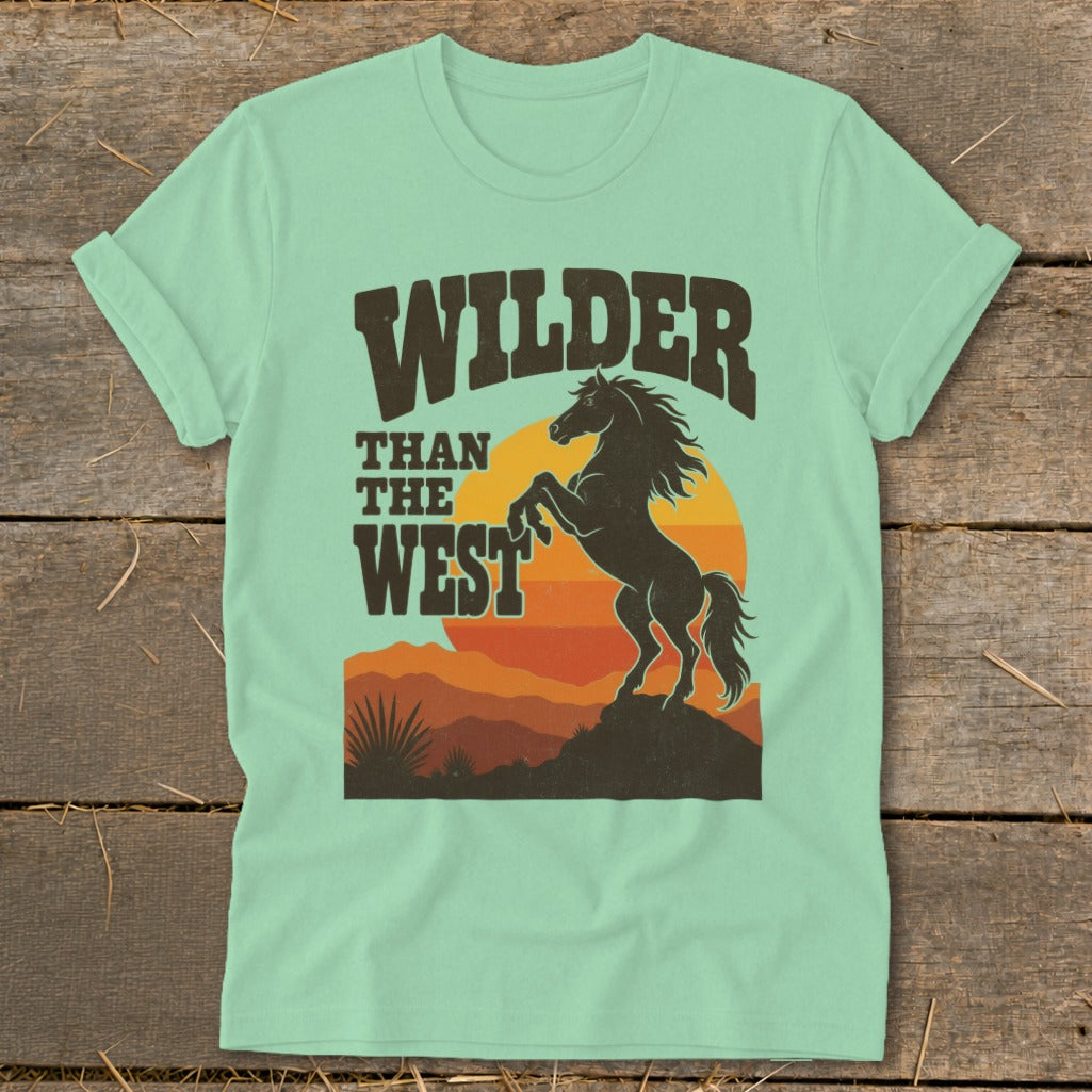 Mint t-shirt with "Wilder Than The West" text and a rearing horse silhouette at sunset.