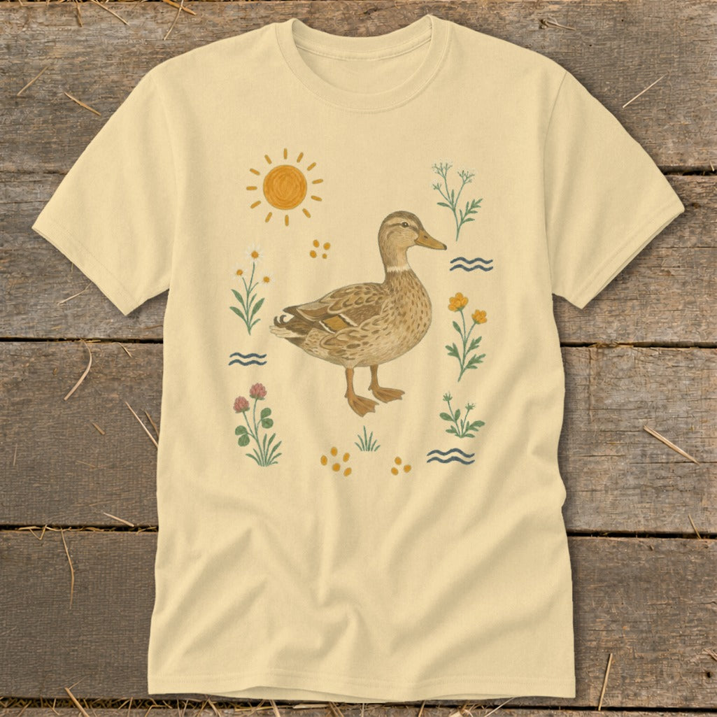T-shirt with a cream background featuring a mallard duck surrounded by a whimsical floral and sun graphic.