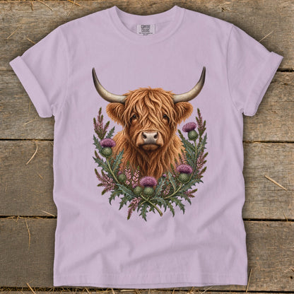 Highland cow with thistle wreath on a lavender t-shirt.