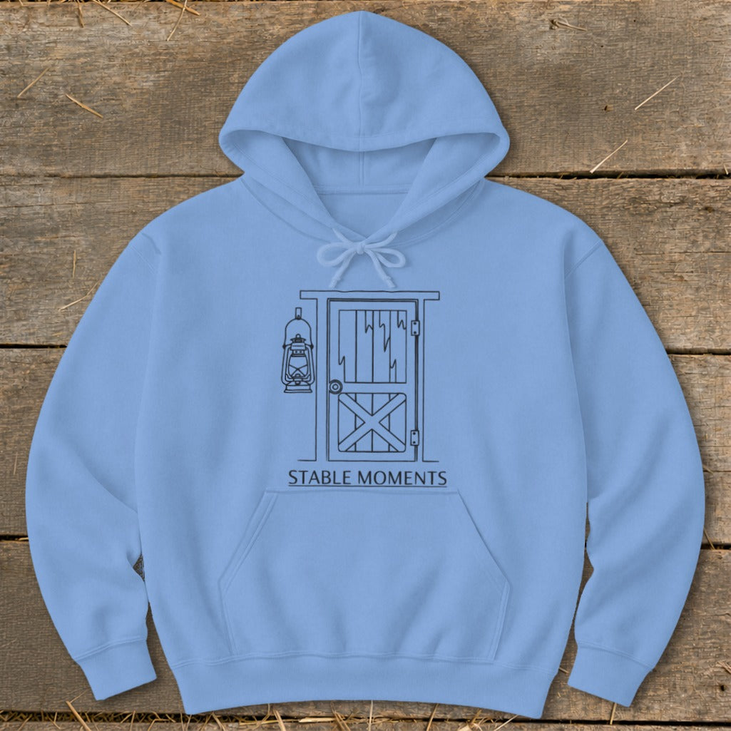 Light blue hoodie with barn door and lantern line art, text "STABLE MOMENTS".