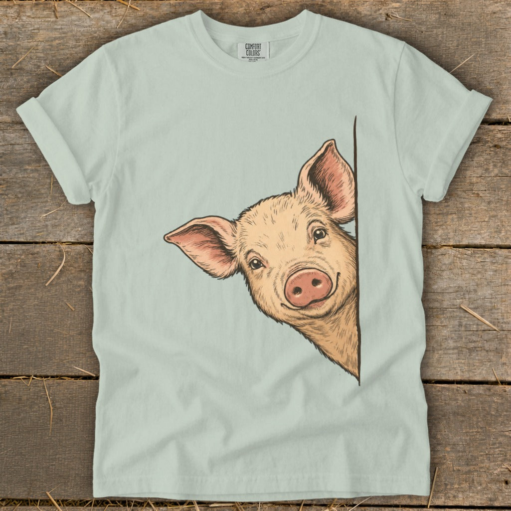 Light blue t-shirt featuring a drawing of a pig peeking from the side.