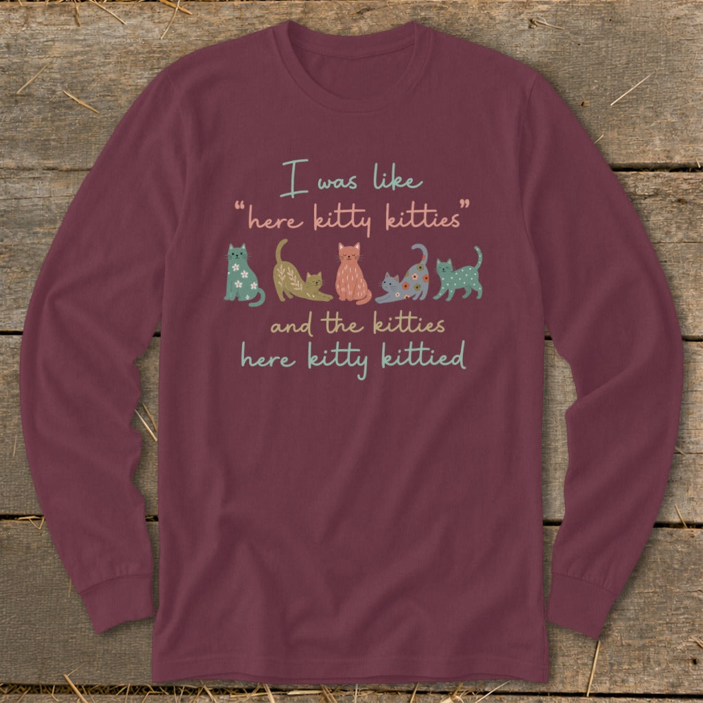 Burgundy long-sleeve shirt with text and illustrations of colorful cats.