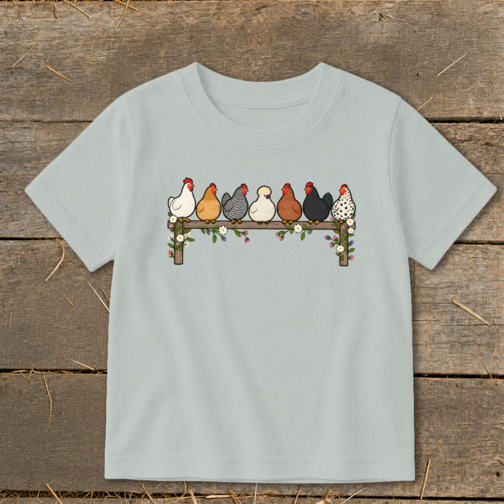 Light gray children's t-shirt featuring a front graphic of seven colorful cartoon chickens perched on a flower-decorated wooden fence.