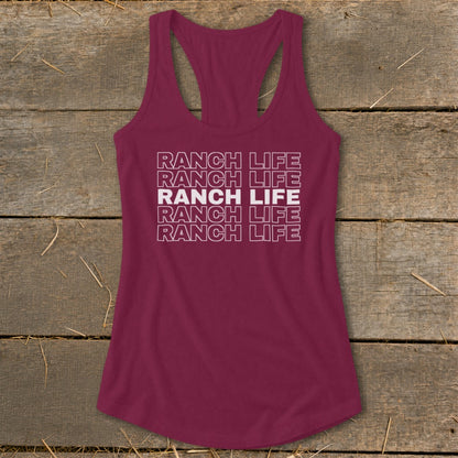 Maroon racerback tank top with repeated white block text reading "RANCH LIFE" laid on a rustic wooden background.