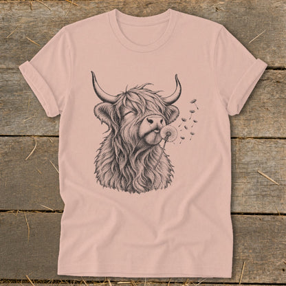 Highland cow with eyes closed blowing dandelion seeds on a light pink t-shirt.