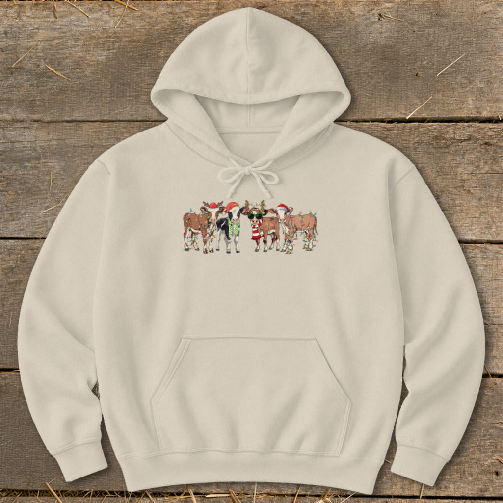 Cream hoodie with a Christmas-themed graphic of cows wearing Santa hats and decorated with lights.