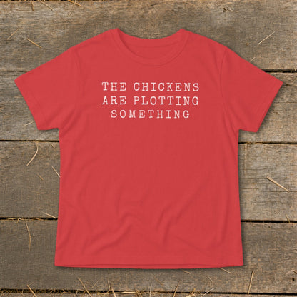 Red t-shirt with white text reading "THE CHICKENS ARE PLOTTING SOMETHING".