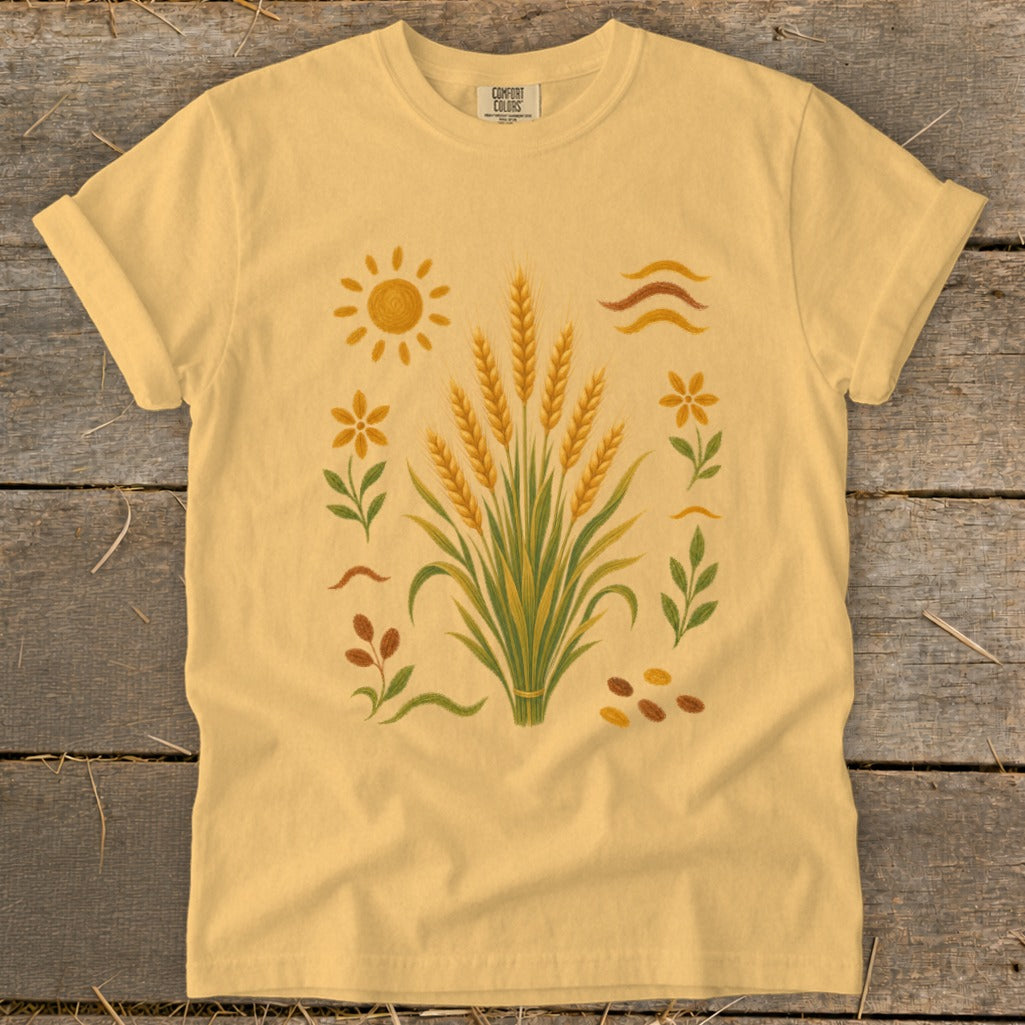 Yellow t-shirt with wheat stalks, sun, flowers, and seeds graphic.