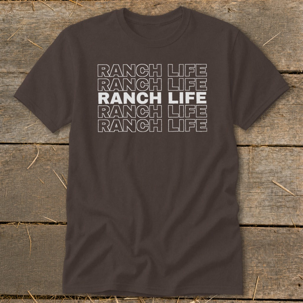 Dark brown t-shirt featuring stacked white text that reads "RANCH LIFE" on a wooden background.