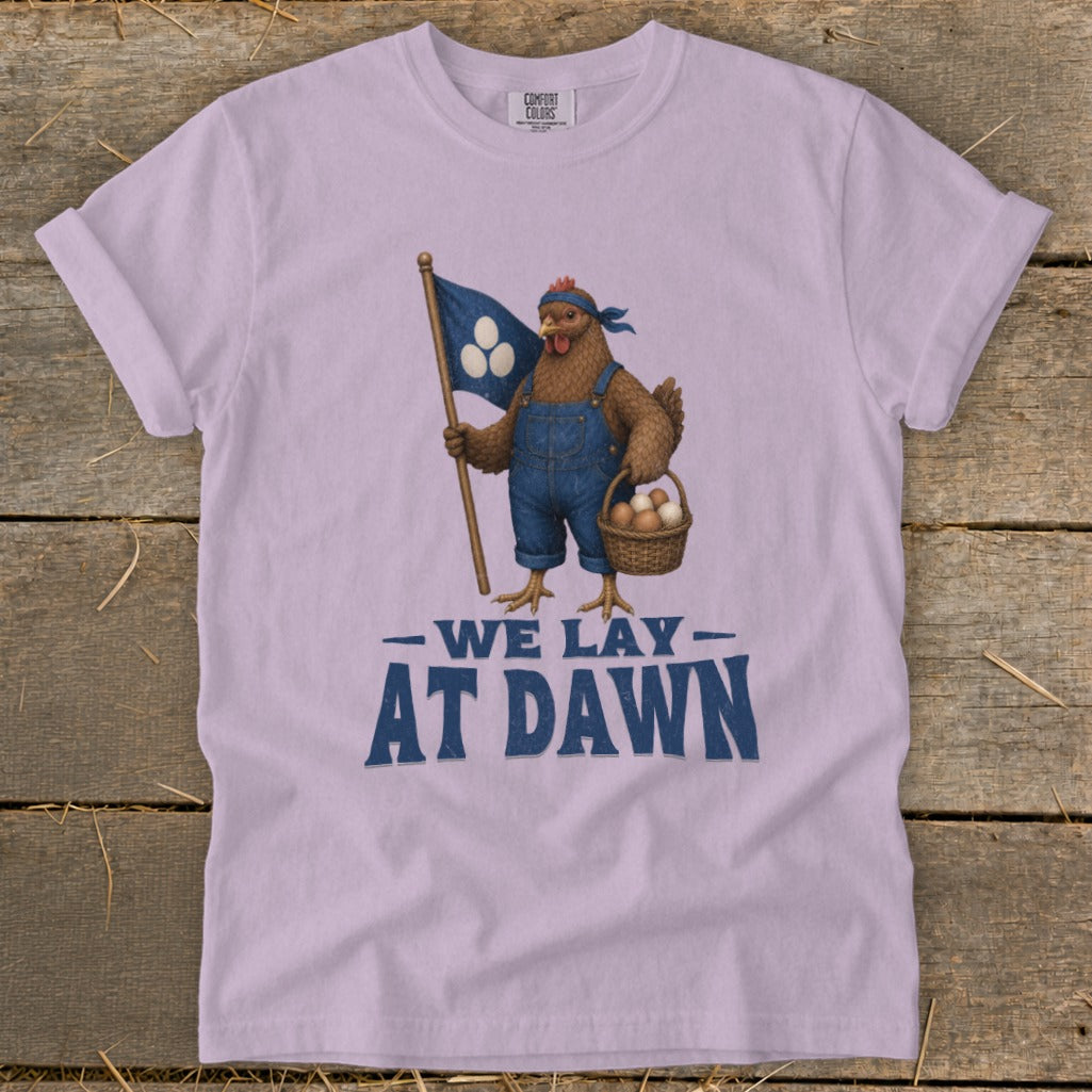 Chicken in overalls holds flag and basket of eggs; text reads "We Lay At Dawn".