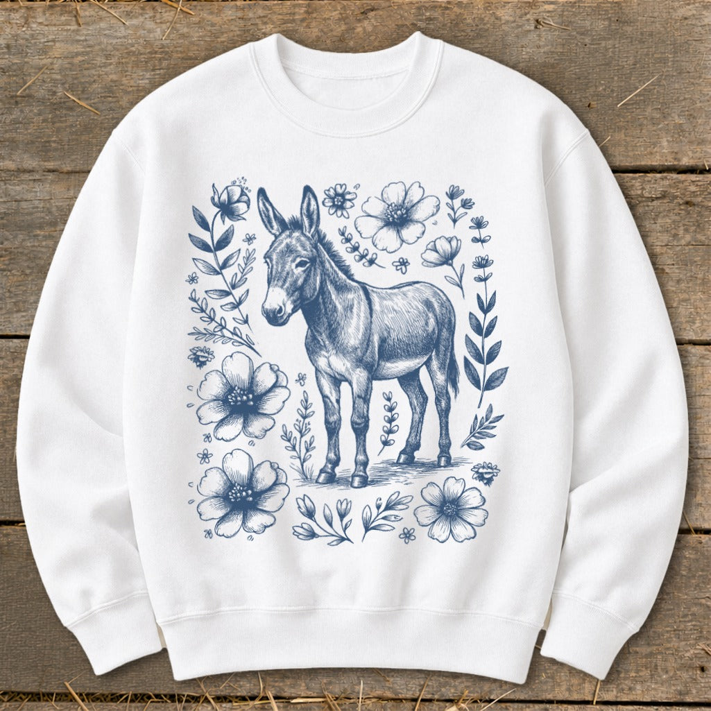 White sweatshirt with a blue sketched donkey surrounded by floral and leafy vines.
