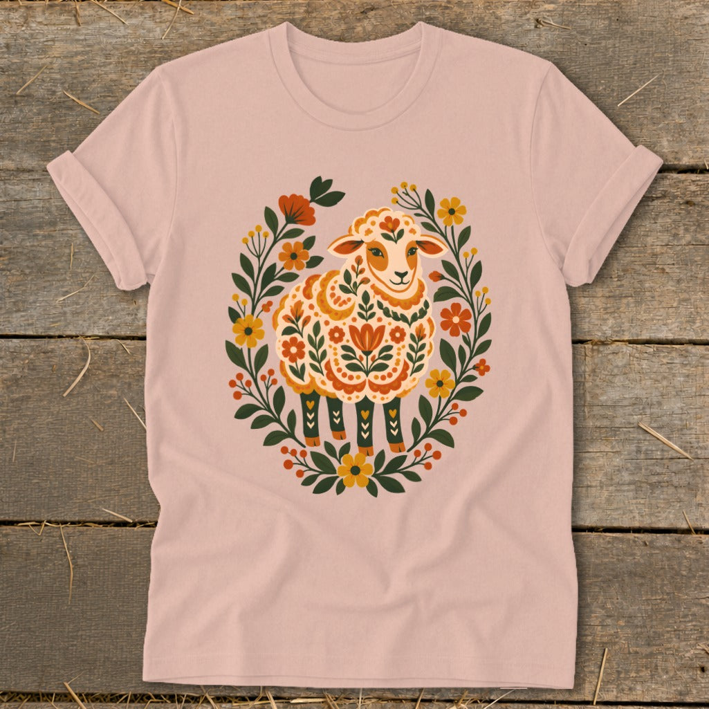 Light pink t-shirt with a colorful sheep illustration surrounded by floral elements.