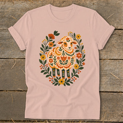 Light pink t-shirt with a colorful sheep illustration surrounded by floral elements.