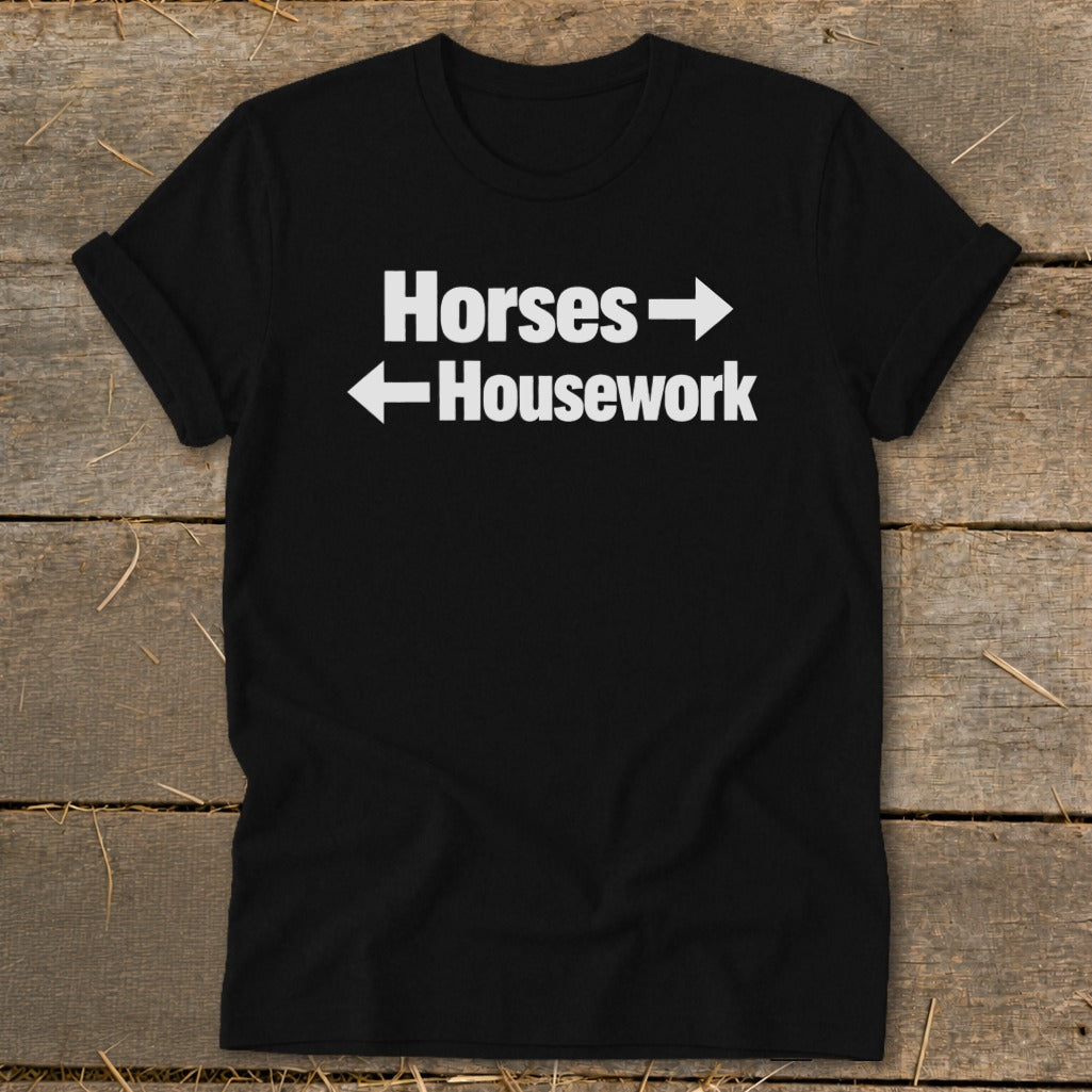 A black t-shirt with rolled-up sleeves features white text that reads Horses with a right-pointing arrow and Housework with a left-pointing arrow.