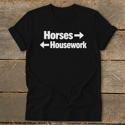 A black t-shirt with rolled-up sleeves features white text that reads Horses with a right-pointing arrow and Housework with a left-pointing arrow.