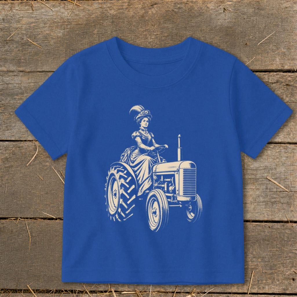 Cream illustration of a woman in vintage attire driving a tractor on a blue shirt.