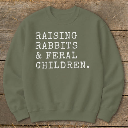 Olive green sweatshirt with white text: "RAISING RABBITS & FERAL CHILDREN."