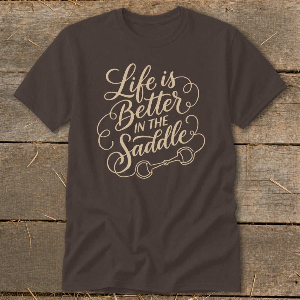 Brown t-shirt with "Life is Better IN THE Saddle" text and horse bit graphic.