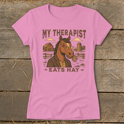 Pink t-shirt with illustration of a horse wearing glasses and eating hay.
