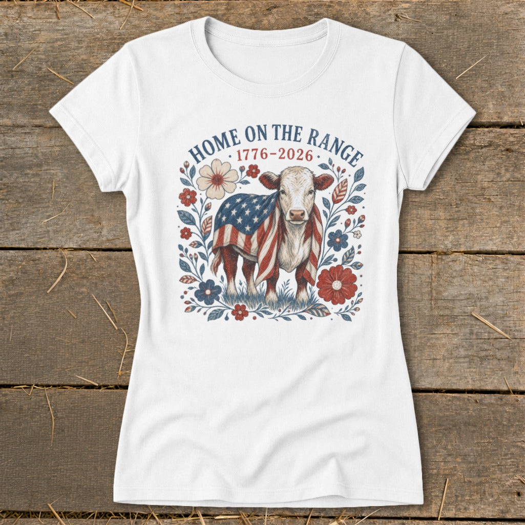 White t-shirt with cow graphic featuring American flag, flowers, and text "HOME ON THE RANGE 1776-2026".