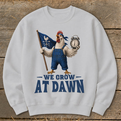 White sweatshirt with chicken graphic and text "WE GROW AT DAWN".