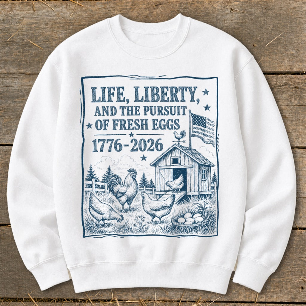 White sweatshirt with "Life, Liberty, and the Pursuit of Fresh Eggs 1776-2026" graphic.