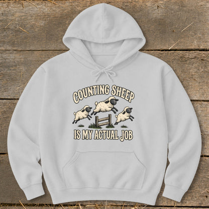 Light grey hoodie with "Counting Sheep Is My Actual Job" text and jumping sheep graphic.
