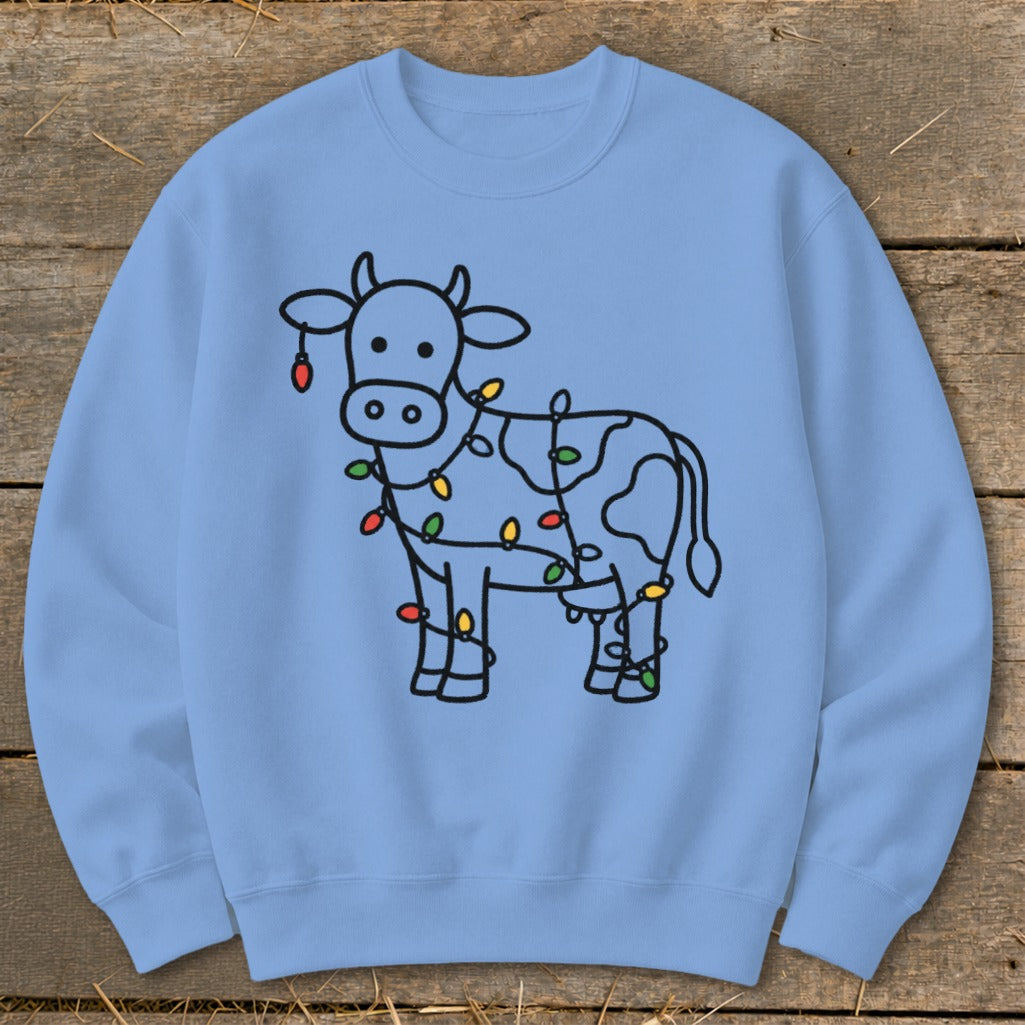 Light blue sweatshirt with a black line drawing of a cow wrapped in colorful Christmas lights.
